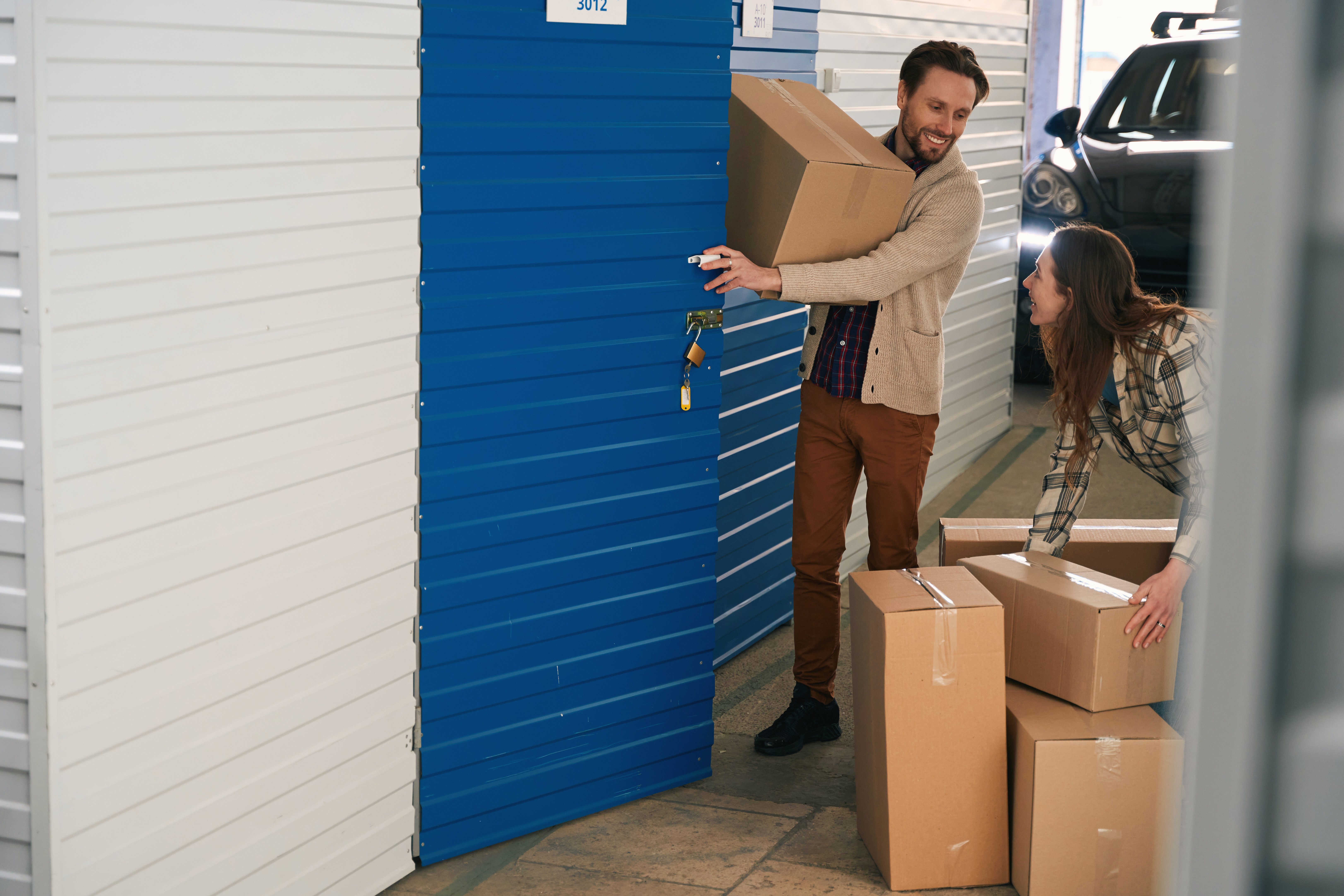 An image of a couple placing items in a small storage unit.